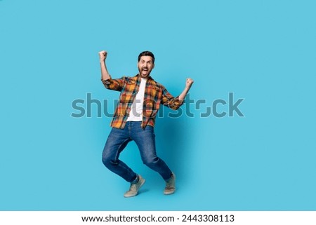 Full length photo of nice young guy raise fists celebrate big luck wear trendy plaid garment isolated on blue color background