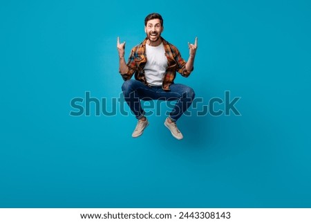 Full length photo of nice young guy jumping excited rocker wear trendy plaid garment isolated on blue color background