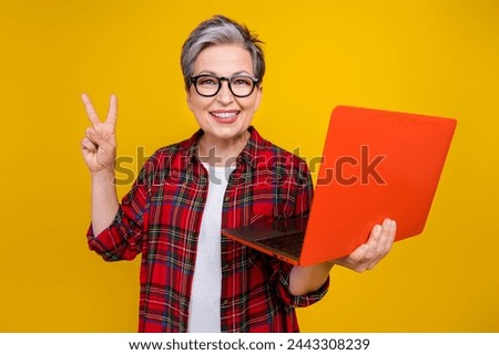 Photo of pretty friendly lady toothy smile hold laptop demonstrate v-sign isolated on yellow color background