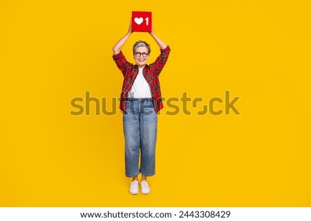 Full size portrait of charming aged lady arms hold like notification logo above head empty space isolated on yellow color background