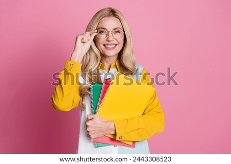 Photo of intelligent positive lady toothy smile hand touch eyeglasses hold notebook empty space isolated on pink color background