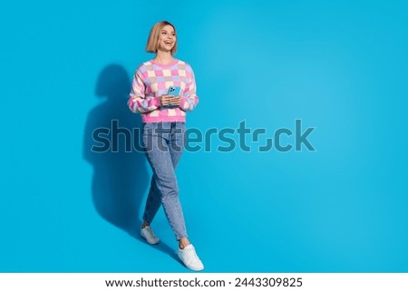 Full size photo of funny woman dressed colorful sweater hold smartphone look at awesome sale empty space isolated on blue color background
