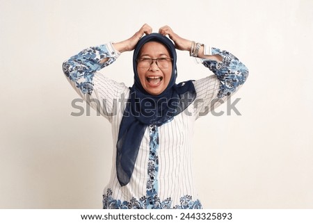 Frustrated asian elderly woman standing while screaming and holding head Royalty-Free Stock Photo #2443325893
