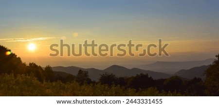 A panorama landscape picture of a sunset in the Shenandoah National Park, during golden hour with sunrays creating a lens flare; copy space, large size