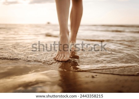 Close- up leg of young woman walking along wave of sea water and sand on the summer beach. Travel, weekend, relax and lifestyle concept.