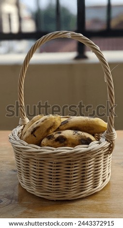 Closeup picture of ripe bananas in the waved bamboo bucket Royalty-Free Stock Photo #2443372915