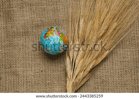 Globe with wheat spikelets on burlap background