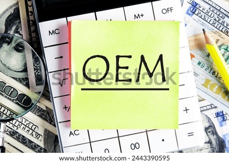 OEM original equipment manufacturer concept. Text on a yellow sticker on the calculator against the background of banknotes