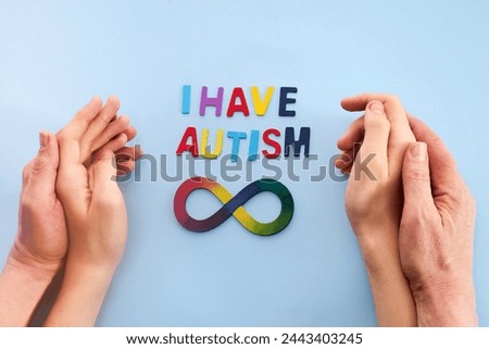 Autistic boy and father hands with rainbow eight infinity symbol. Autism awareness day symbol.