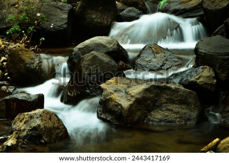 abstract nature background long exposure of a waterfall with a small river flowing. with a bunch of rocks.sstkbackground