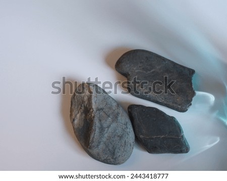 Rocks and reflections on a white background for a minimalist product background.      
