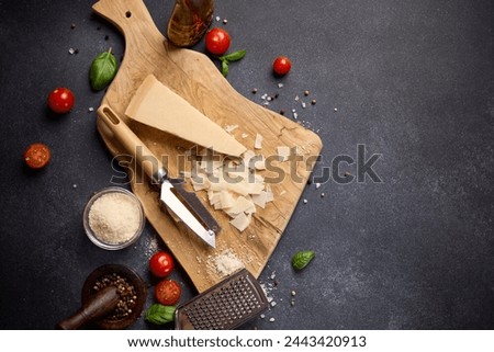 Piece of Traditional Italian Parmesan Hard cheese on a wooden cutting board at domestic kitchen Royalty-Free Stock Photo #2443420913