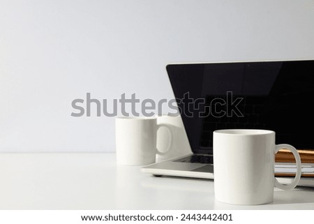 White cups on a table with a laptop