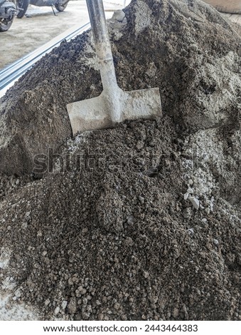 A shovel stuck in a sand dune, building background, stock photo.