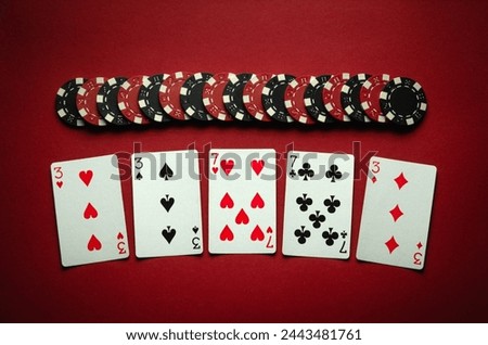 Winning at the poker club. Combination of full house or full boat playing cards and chips on a red table. Winning at a casino depends on luck.