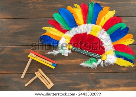 Indian headdress roach and traditional toys noisemakers for Jewish holiday Purim over dark wooden background.