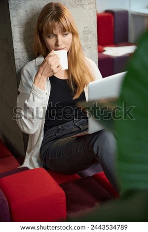 Woman clothing designer working on laptop and drinking coffee