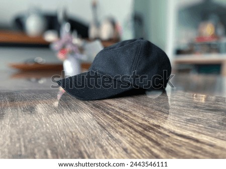 Interior top view visual image photo of a black cap hat down on a wood table in a house in close up with nobody around but during the bright day light