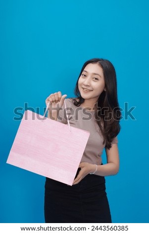 beautiful asian woman holding shopping bags isolated on blue background