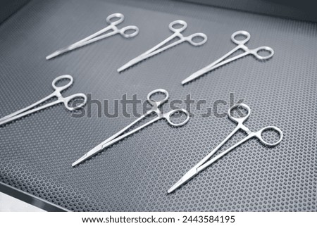 Pharmaceutical factory for production of medical instruments, sterile steel surgical clamps on conveyor belt, top view. Royalty-Free Stock Photo #2443584195