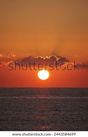 Sun at sunset between cloud and sea Royalty-Free Stock Photo #2443584699