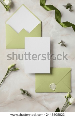 Wedding stationery set. Flat lay olive envelopes, blank wedding invitation card, flowers on marble background. Royalty-Free Stock Photo #2443605823