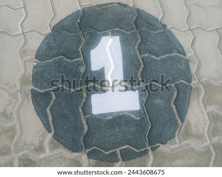 Crisp white parking space number "1"painted on a gray concrete tuff tile surface in a parking lot. This high-resolution royalty-free image features a clear, crisp white number "1" professionally paint