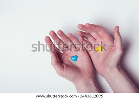 female hands hold two hearts blue and yellow, Ukraine flag colors, symbol of hope, help, protection, support, confrontation and opposition isolated on white background