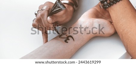Mehendi master drawing henna tattoo on female hand,mehendi art 