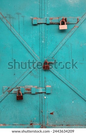 A locked green door with 3 locks on it 