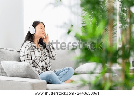 Chinese woman relaxed on the sofa listening to music with headphones