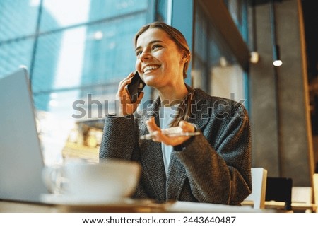 Young female freelancer talking with client and work on laptop in cafe. Distance work concept