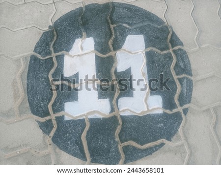 Clear and Simple Parking Spot Number 11 in White Paint,A high-resolution, royalty-free image featuring a crisp, white parking spot number "11" painted on a rough, textured tuff tile surface.
