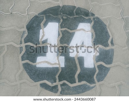Close-up of Clearly Marked Parking Spot 14 in White Paint on Textured Tuff Tile Parking Lot Surface, Royalty-free high-resolution stock photo depicting a designated parking space clearly marked with.