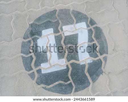 White painted parking space number 17 on a textured concrete surface,This royalty-free stock photo features a clearly visible parking space number, "17," painted in white on a textured concrete surfac