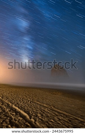 Night astro long exposure photography of famous Haystack Rock in Cannon Beach Oregon, and the Milky Way stars above it