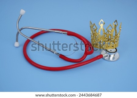 Gold crown with red stethoscope on blue background. Health of royal family concept.	