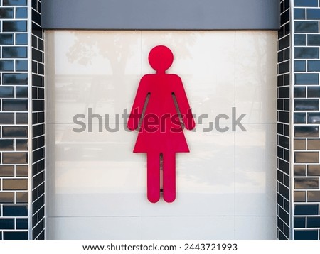 Large red women's toilet sign on a tiled wall. Copy space background