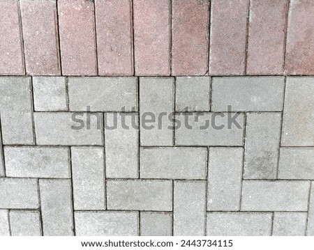Close up top view on the stone road. The modern pavement. Red and white square cobblestone sidewalk. Granite stone block wall rough textured background