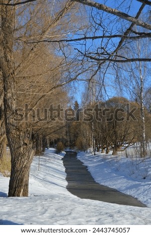 Beautiful winter landscape with white snow, trees and stream against bright blue sky. Beautiful and bright winter weather in the small town of Varkaus, Finland.