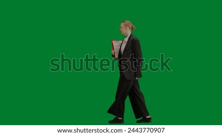 Portrait of female in suit on chroma key green screen. Blonde business woman in formal outfit walking and dancing, smiling positive expression. Side view.
