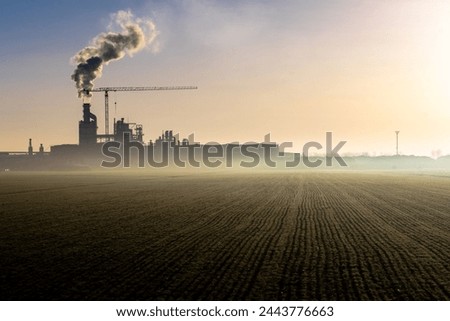 a factory heavily pollutes the air in the Po Valley in Italy Royalty-Free Stock Photo #2443776663
