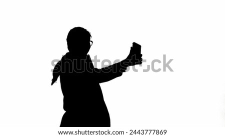 Business woman in formal outfit holding smartphone and taking selfie pictures. Black silhouette on a white isolated background.