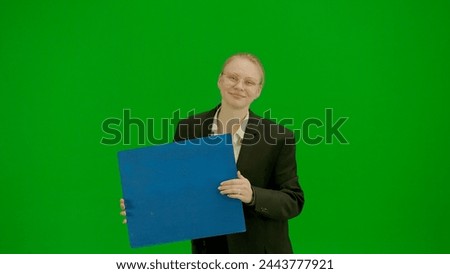Portrait of female in suit on chroma key green screen. Blonde business woman in formal outfit holding advertisement board, dancing smiling face.