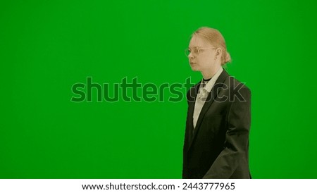 Portrait of female in suit on chroma key green screen. Blonde business woman in formal outfit walking with confident focused face expression.