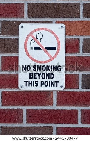 Faded and cracked no smoking sign on a brick wall