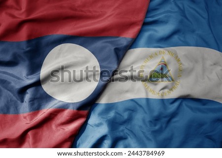big waving national colorful flag of nicaragua and national flag of laos. macro