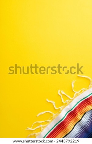 Cinco de Mayo event portrayal. Top view vertical photo capturing party must-haves: bright striped serape on a sunny yellow background, with space for captions