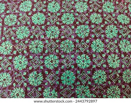 Repetitive patterns of turquoise flowers and geometric shape on purple base fabric 