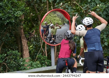 group of three young asian cyclists taking a funny selfie together outdoors on rural road